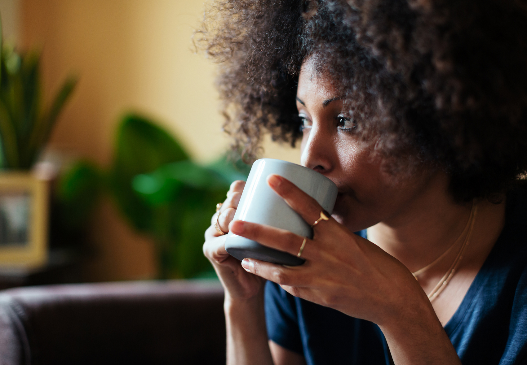 woman sipping out of a coffee mug holding it with both hands